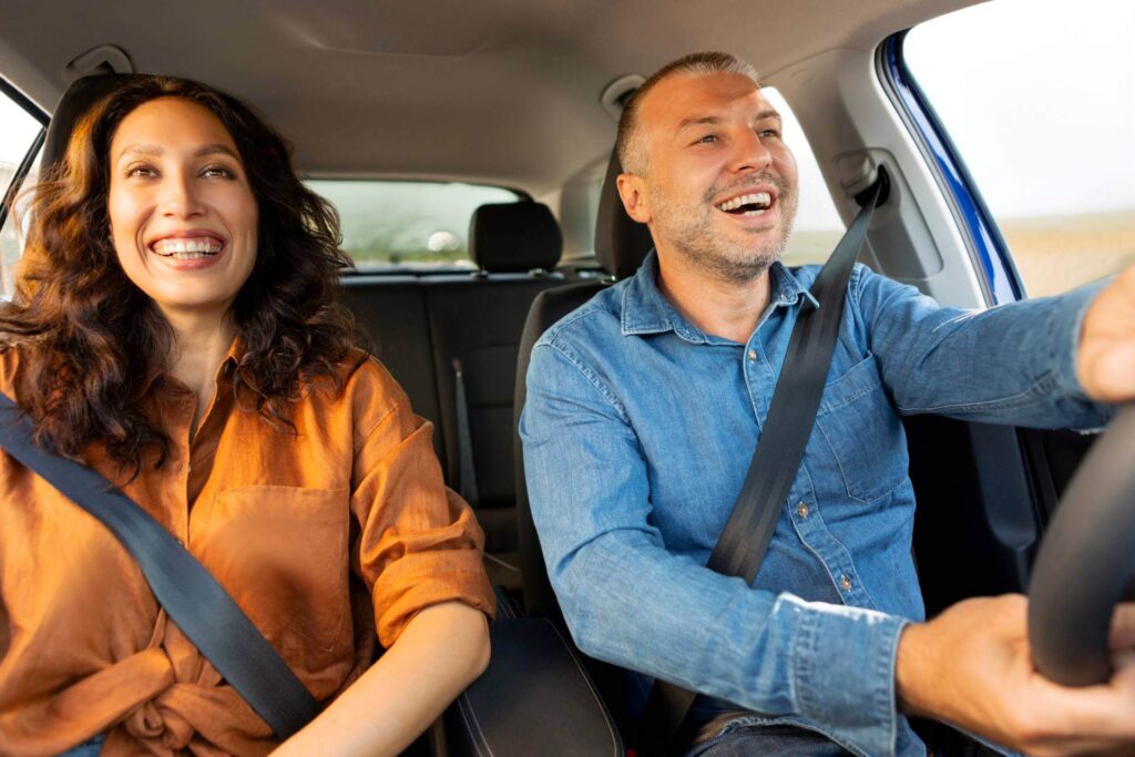 Couple driving off in their first car with auto financing through Drive Next.